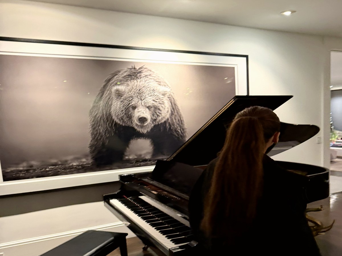 Courtney seated at a grand piano in a warm private musical space