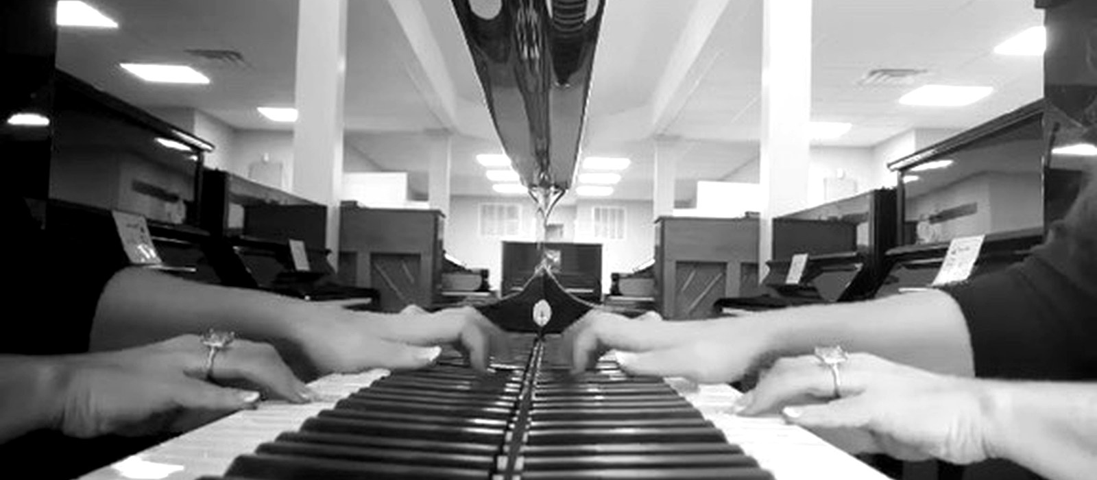 Hands playing piano keys reflected in the piano finish