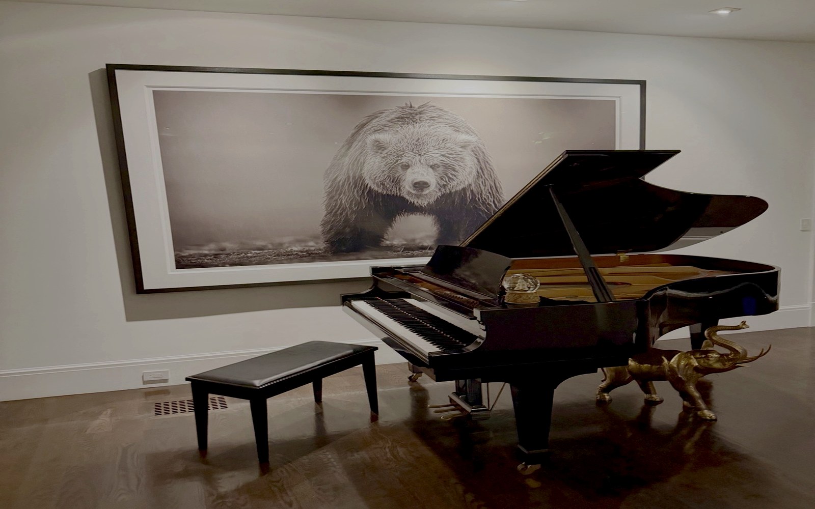 Courtney seated at a grand piano in a warm private musical space
